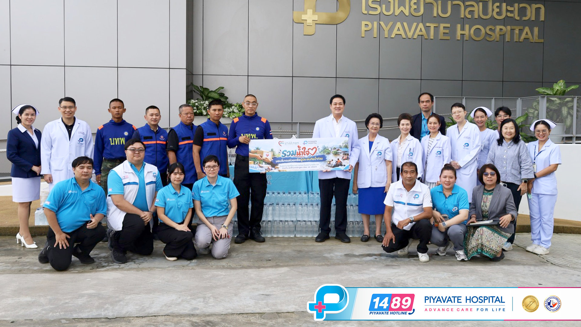 ทีมแพทย์ แพทย์ และอาสาสมัครโพสต์ท่าหน้าโรงพยาบาลปิยะเวทพร้อมถือป้ายบริจาคช่วยเหลือภัยน้ำท่วม