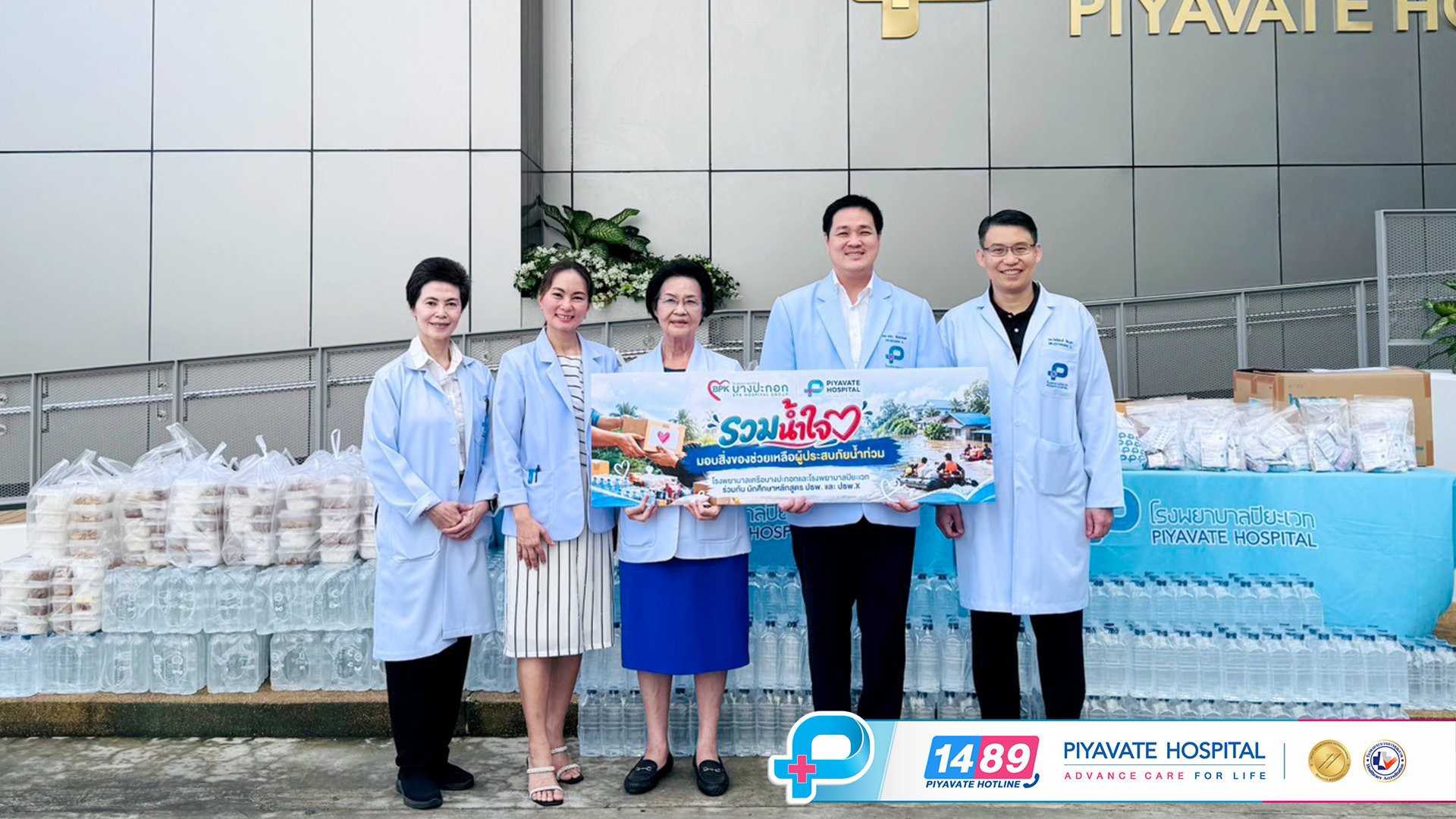 พญ.เจรียง จันทรกมล, นพ.พณะ จันทรกมล และคณะแพทย์ผู้บริหารถือป้ายช่วยเหลือผู้ประสบภัยน้ำท่วม รวมน้ำใจ