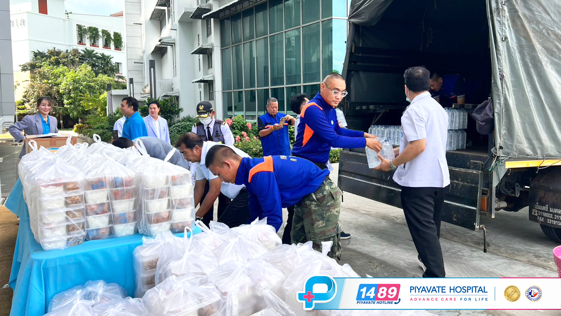 อาสาสมัครและเจ้าหน้าที่โรงพยาบาลกำลังช่วยกันยกแพ็คพัสดุน้ำดื่มและอาหารขึ้นรถบรรทุกขนย้ายสิ่งของช่วยเหลือ