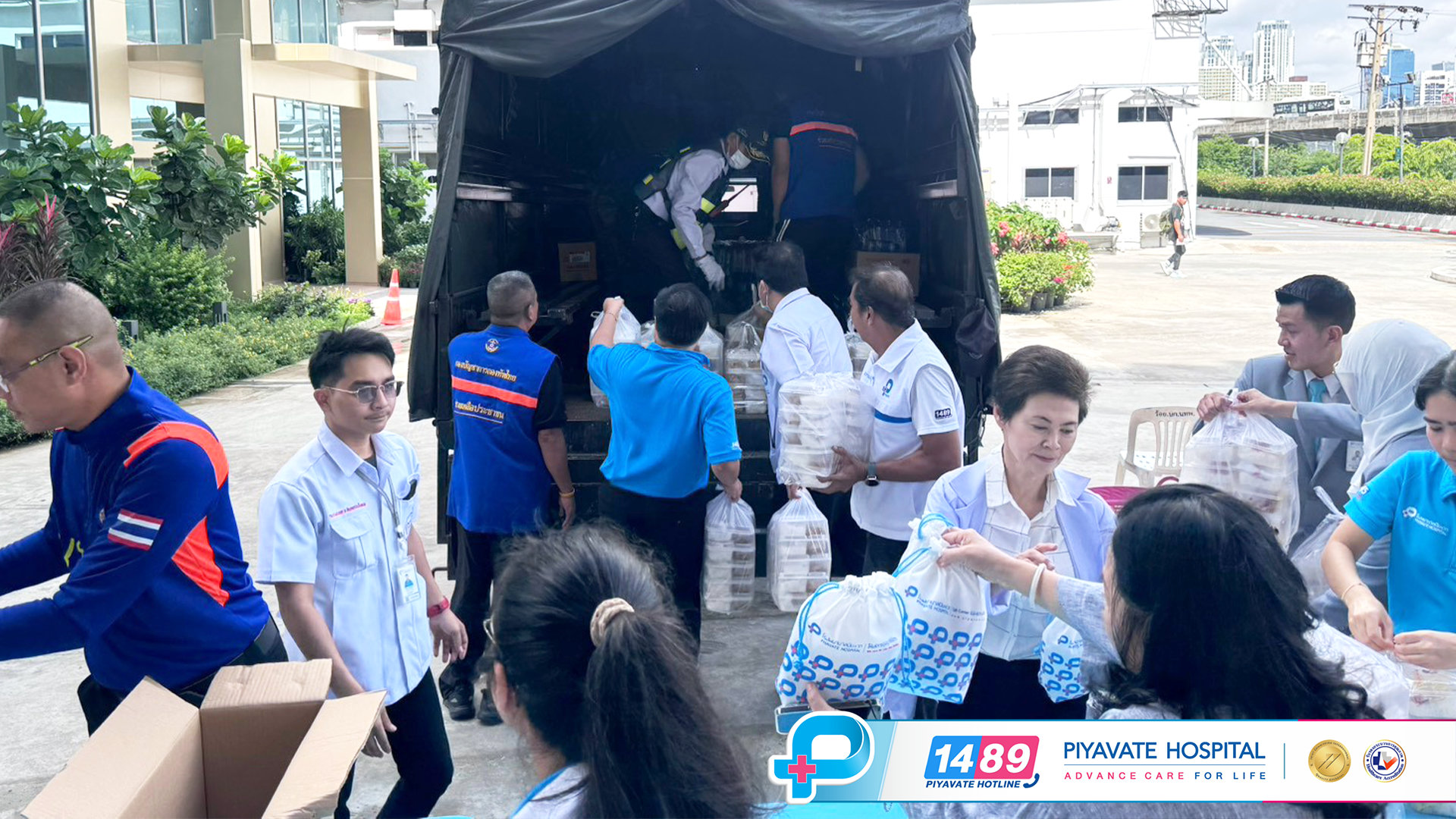 เจ้าหน้าที่โรงพยาบาลและอาสาสมัครแจกจ่ายสิ่งของบรรเทาทุกข์และถุงยังชีพใกล้รถบรรทุกขนส่ง