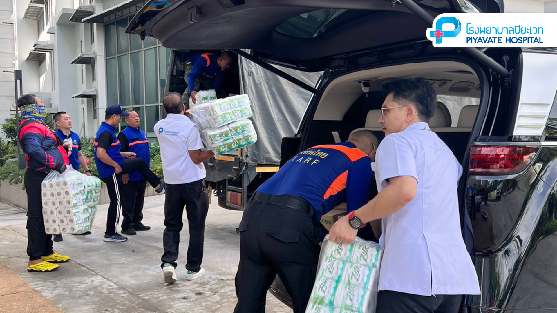สมาชิกในทีมกำลังขนกล่องสิ่งของจำเป็นและกระดาษชำระม้วนขึ้นหลังรถ